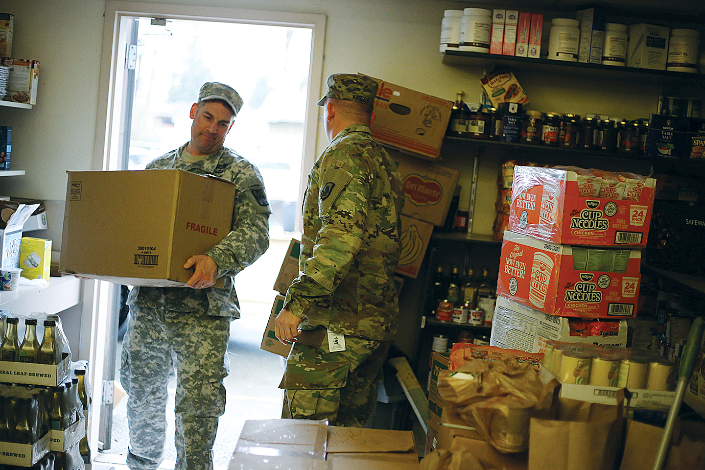 Soldier stands at a door filled with food at the food bank.